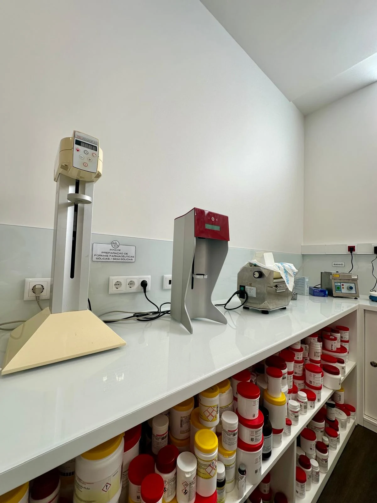 Bancada com equipamentos de preparação e prateleiras de matérias-primas do laboratório